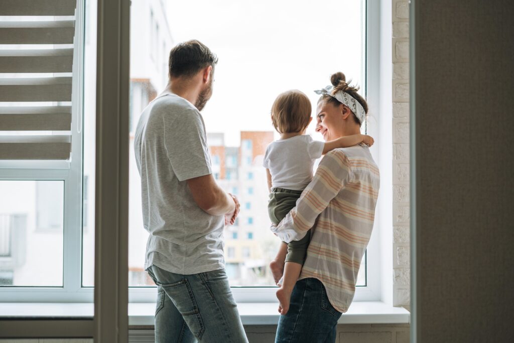 2 parents holding their baby looking out of the window